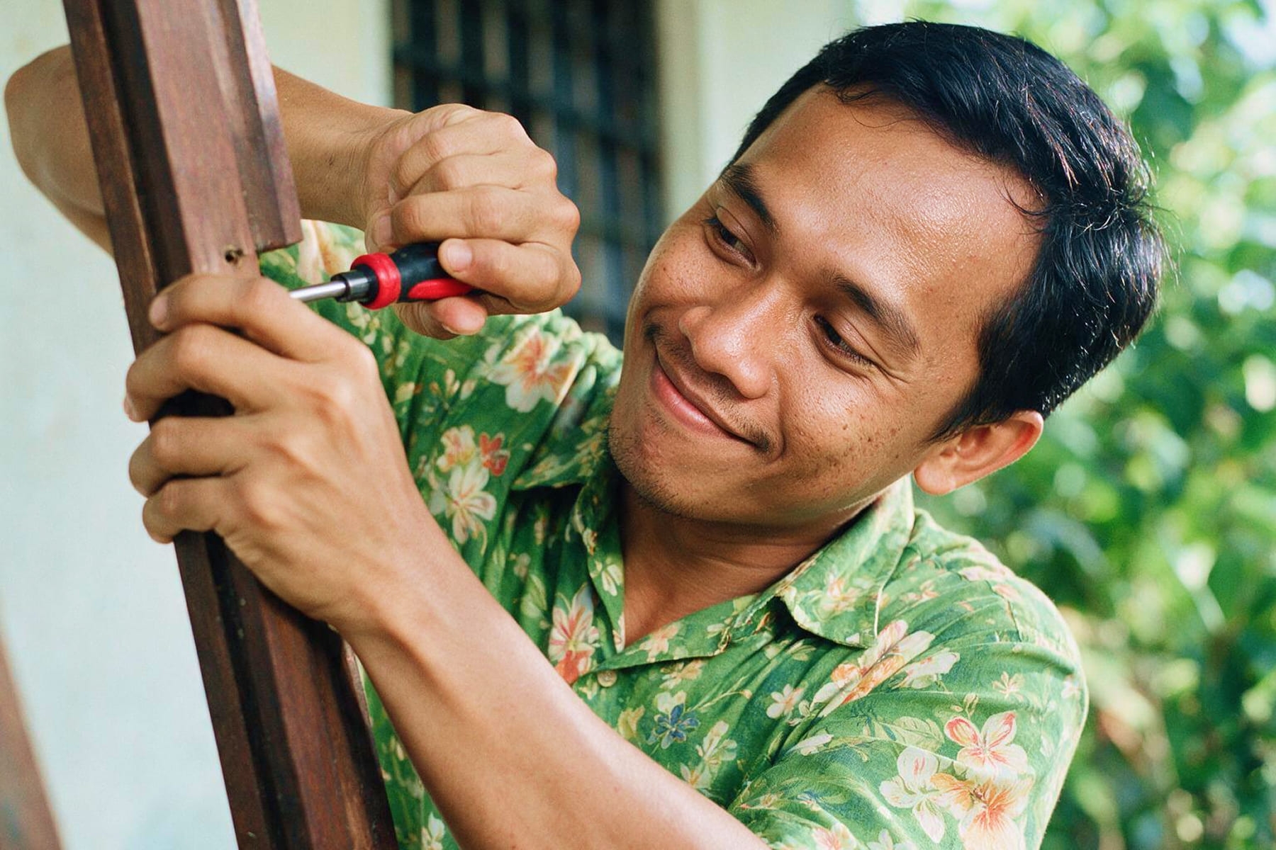 a young man in a hawaiian shirt holding a drill