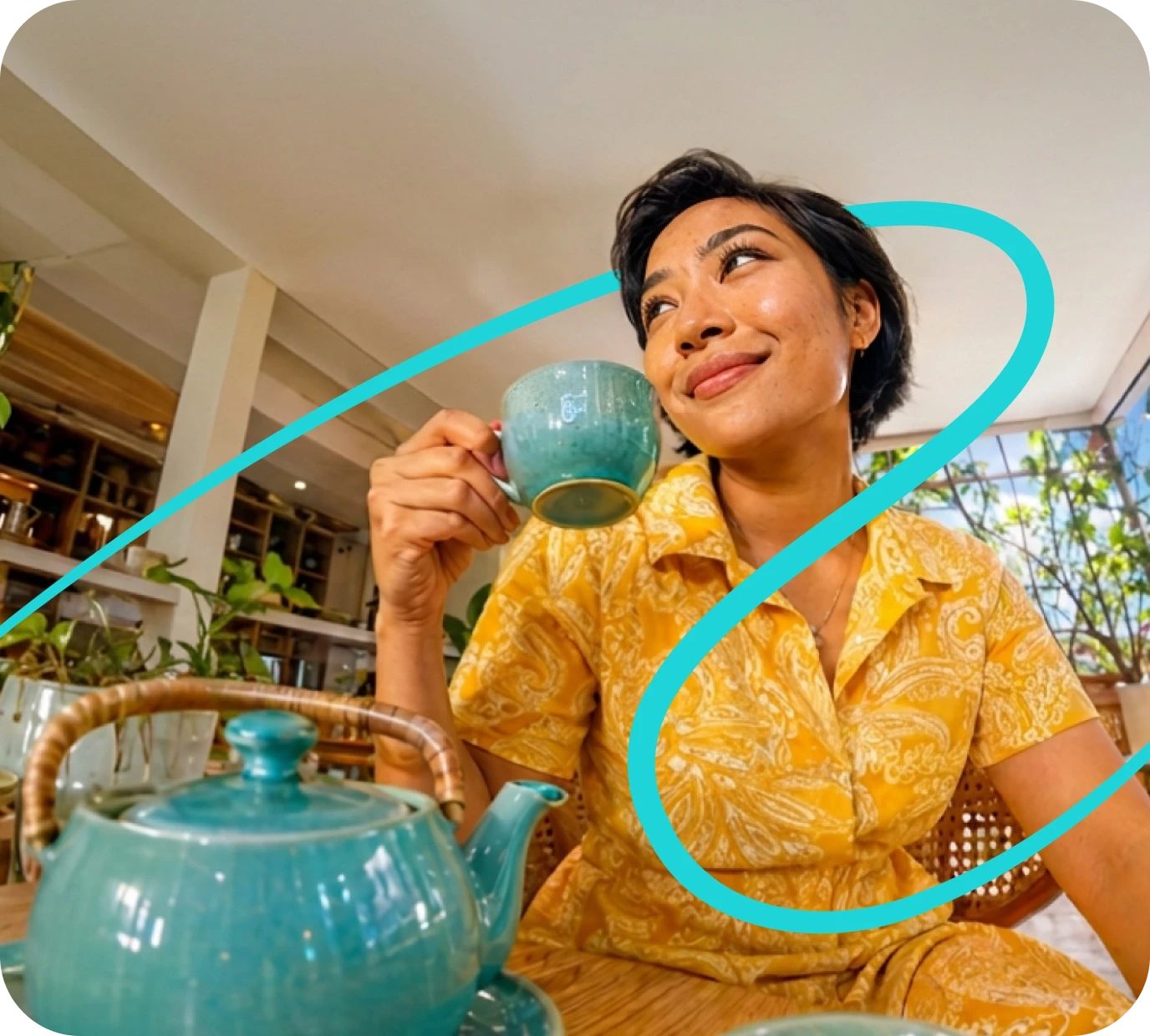 a woman sitting at a table with a blue teapot and a cup of tea