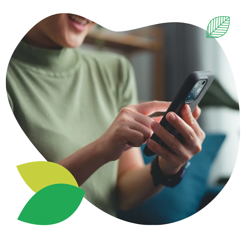 Frau hält lächelnd Smartphone in der Hand.