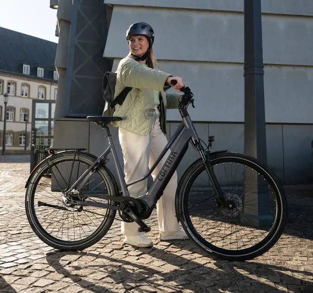 vrouw staat naast een cortina e-mozzo woon-werkfiets