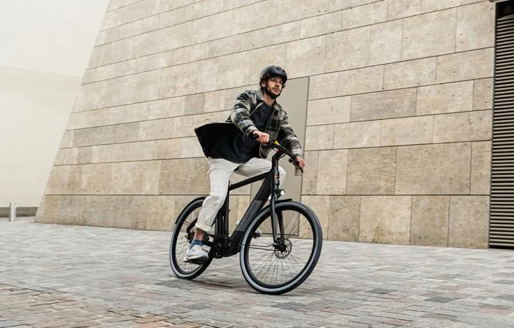 Man met helm op fietsend in de stad op een Cortina E-Blau Jet Black herenfiets