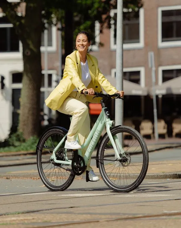vrouw fietsend op een cortina e-lett pastel green matt damesfiets